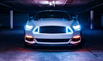 A mustang in a garage with its headlights on
