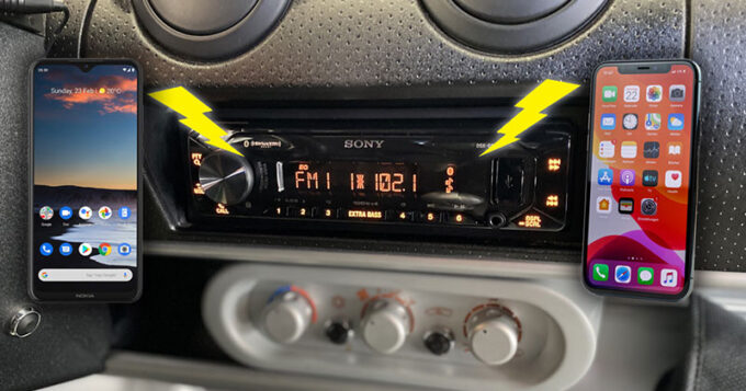 An old time car radio installed and two cell phones with lighting bolts connecting them to the radio system